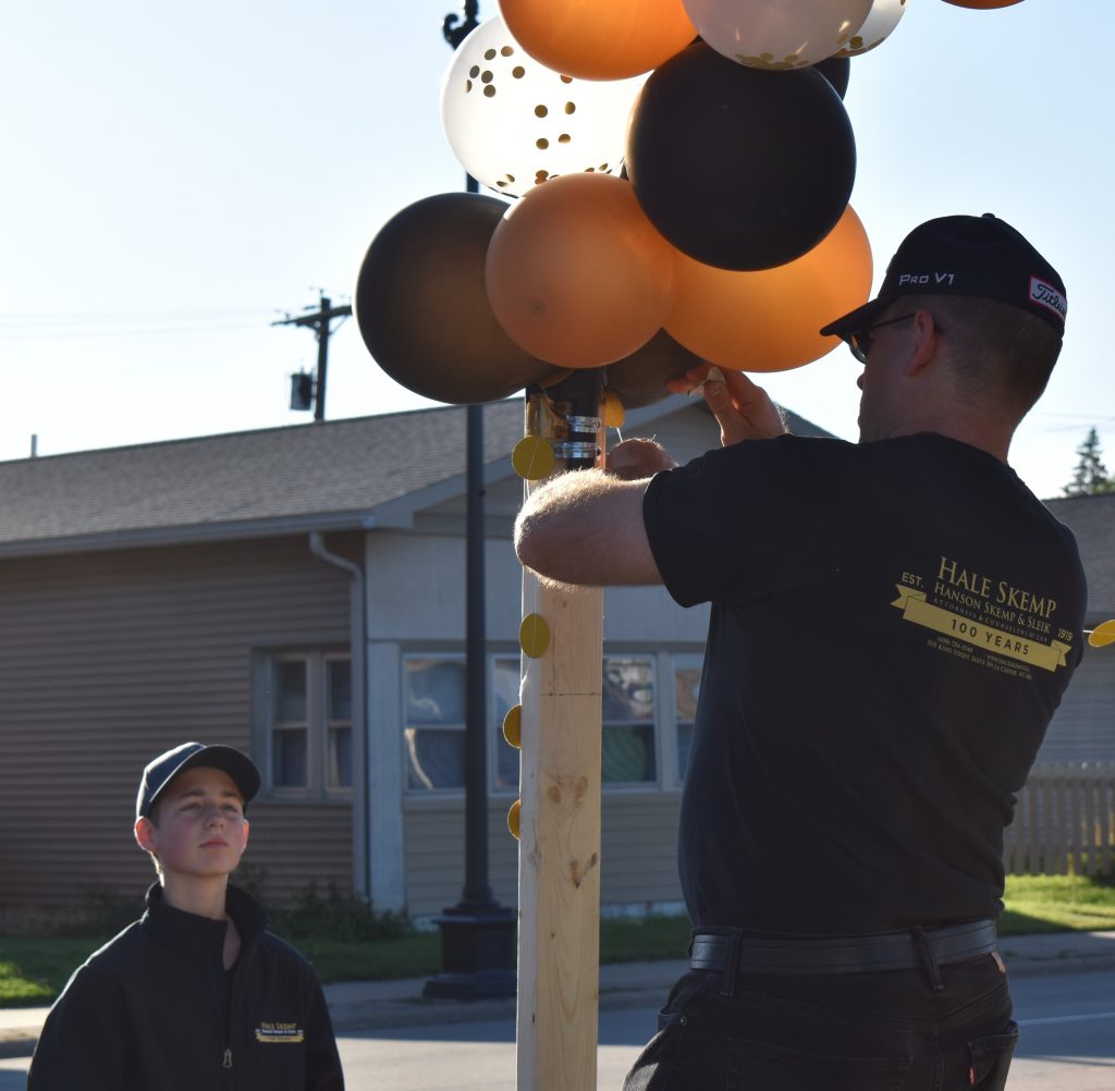 Man decorating a parade float while boy observes.