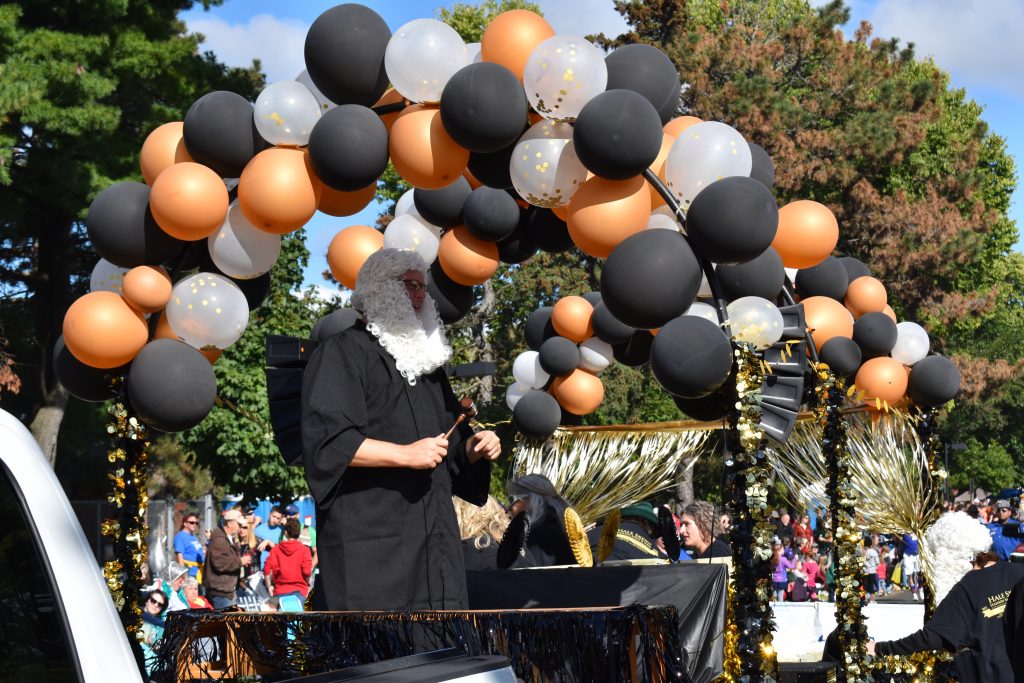 Man stands on float in black robe and barrister wig.