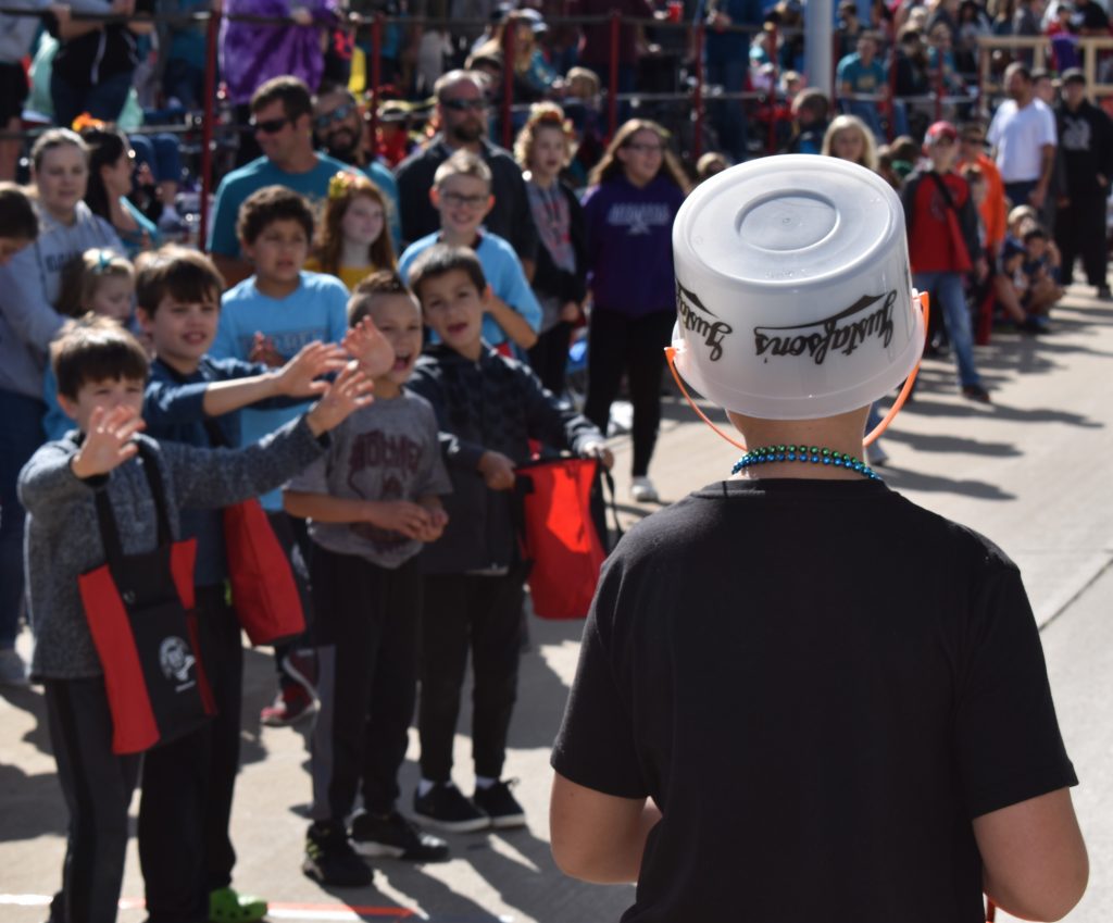 Boy on parade route as crowd shouts for candy.