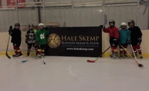 Youth hockey players stand next to sign.